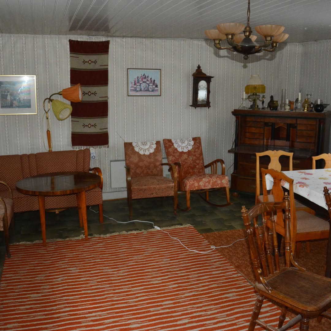 Äldre vardagsrum med tapet och trämöbler före renovering