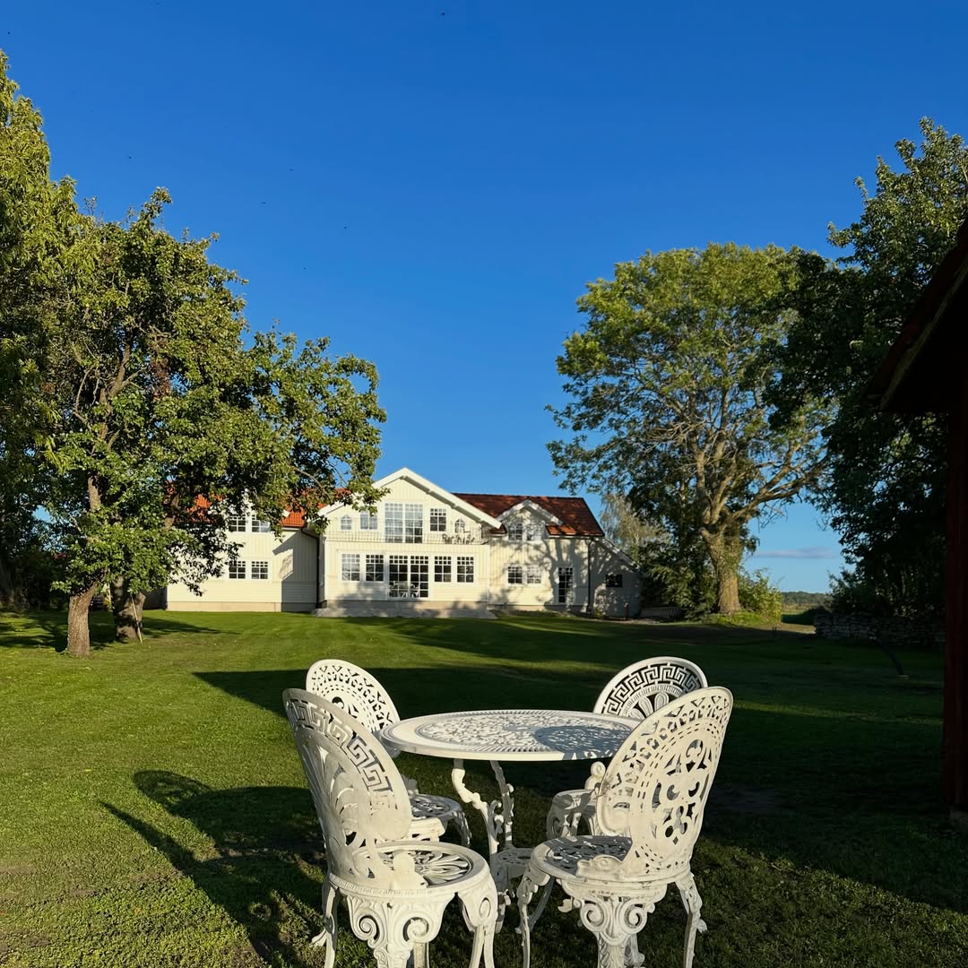 Ljus villa med rött tegeltak efter ombyggnad, sedd från trädgården